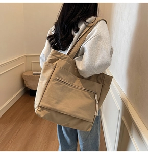 Détail du sac cabas en toile kaki avec grande poche zippée et tirettes à nœuds décoratifs
