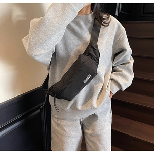 Détail d'un sac bandoulière noir avec sangle en nylon ajustable et imprimé texte blanc