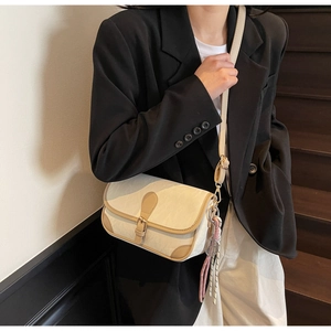 Detail of cream flap crossbody bag with khaki trim and mini tennis racket pendant charm