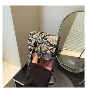 Detailed close-up of snakeskin pattern and silver metal buckles on a mini crossbody bag