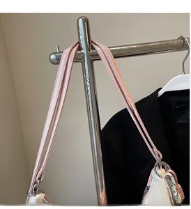Detail of pink leather handles with stitching and woven rope charm on a large tote bag