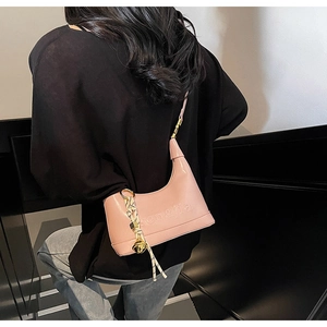 Detailed back view of pink patent leather shoulder bag with logo and braided strap charm
