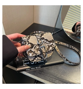 Detail of snake print saddle bag with silver metal ring buckle on a fashion book