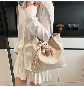 Detail of cream large tote bag in glossy PU leather with a cute brown teddy bear charm