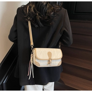 Close-up of a cream-colored pleated crossbody bag with tan leather trim and striped scarf