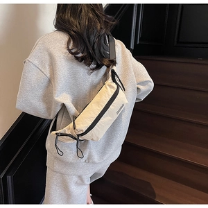 Détail d'un sac bandoulière minimaliste en nylon crème avec fermetures éclair noires