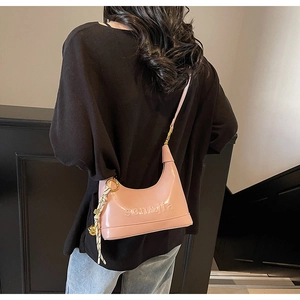 Close-up of pink hobo bag featuring debossed logo and decorative gold bell tassel