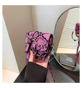Detailed view of pink and black snake pattern crossbody bag with silver buckle straps