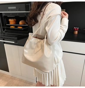 Chic cream leather tote bag with side pleats shown in a modern lifestyle setting