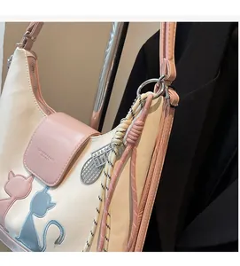 Close-up of color-block tote bag featuring cat embroidery and woven rope details