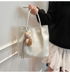 Detail of off-white tote bag with a cute bear charm and woven drawstring accents