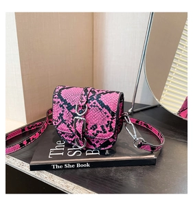 Detail of mini saddle crossbody bag featuring pink snakeskin print and silver buckle