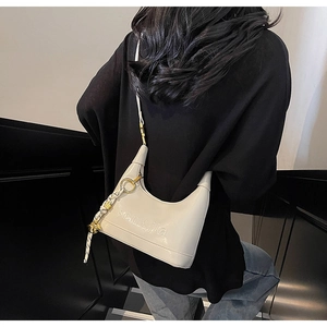 Detail view of cream hobo bag featuring embossed lettering and a woven pendant