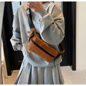 Détail du sac bandoulière orange foncé avec fermetures éclair noires et sangle en nylon