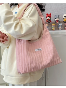 Close-up of pink pleated fabric texture and brand label on a large shoulder tote bag