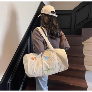 Dettaglio della borsa da viaggio in tela crema con ricami colorati e logo sorridente