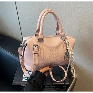 Detailed shot of pink Boston bag with embossed lettering and woven rope charm detail
