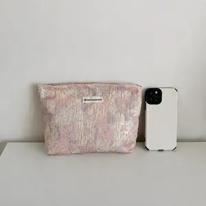 Neceser de tejido compacto con comparación de tamaño con un smartphone en toma de estudio