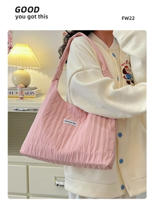 Detailed close-up of pink pleated tote bag with woven label and fabric texture