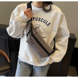 Détail d'un sac bandoulière en nylon gris avec sangle réglable et texte de marque