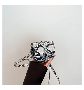 Close-up of black and white snakeskin print mini bag with silver metal buckle detail