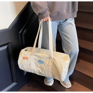 Dettaglio di una grande borsa da viaggio crema con ricami su una scala in legno