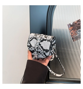 Close-up of black and white snakeskin print mini saddle bag with silver buckle