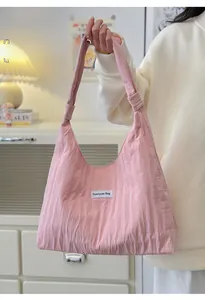 Detail of light pink pleated tote bag with branded fabric label and knotted strap