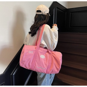 Dettaglio della borsa da viaggio in tela rosa con lettere ricamate e tracolla larga