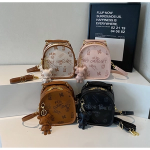 Detail of four stylish mini backpacks in various colors with cute bear charms and graffiti