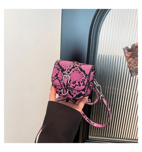 Detail of mini pink snakeskin saddle bag with silver buckle and adjustable shoulder strap