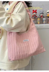 Detailed macro view of pink pleated nylon tote bag texture and white woven brand label