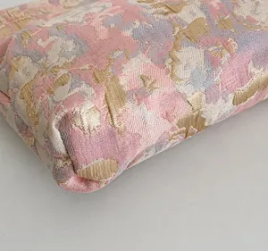 Vista macro de costuras precisas y tejido jacquard floral para una bolsa de maquillaje