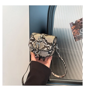 Close-up of mini faux snakeskin saddle bag with silver buckle and crossbody strap