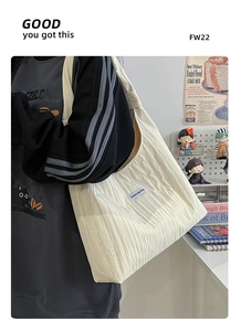 Detail shot of the vertical pleated texture and side label on a white oversized tote bag