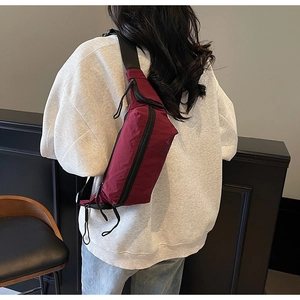 Sac bandoulière en nylon bordeaux avec sangle réglable et détails zippés portés par mannequin