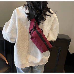 Gros plan d'un sac de poitrine en nylon bordeaux avec sangle réglable et logo