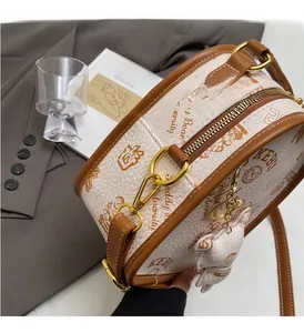 Close-up of premium gold-tone hardware and brown bear charm on cream crossbody bag