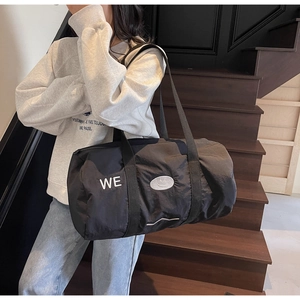 Dettaglio della borsa da viaggio nera con ricamo WE e toppa a forma di faccina