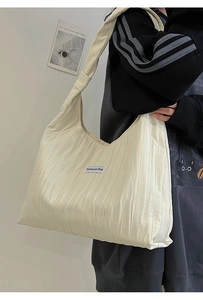 Close-up of cream pleated tote bag featuring a minimalist fabric brand label on the front