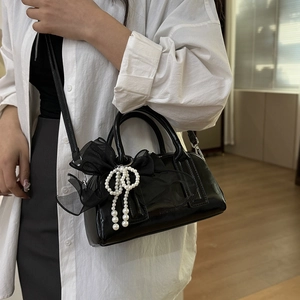 Sac Boston vintage noir avec nœud en tulle et pendentif perle porté par mannequin