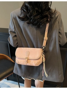 Women stylish light pink small square crossbody bag with gold buckle on a grey blazer