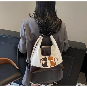 Detail of a chic two-tone backpack with cat silhouette appliqués on the back of a model