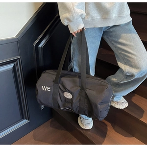 Dettaglio borsa da viaggio in nylon nero con ricamo WE e patch smiley su scale