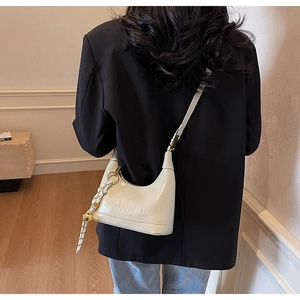 Close-up of cream glossy leather handbag featuring embossed logo and woven rope detail