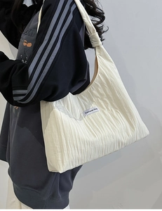 Detail of white pleated tote bag showing fabric texture and Duociyuan brand label