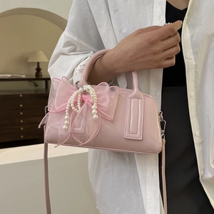 Détail du sac Boston en cuir verni rose avec un grand nœud en tulle et perle