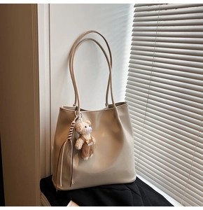 Minimalist beige tote bag made of synthetic leather with a cute plush bear pendant accessory