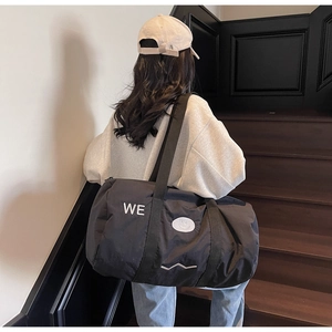 Dettaglio di una grande borsa da viaggio nera con grafica WE trendy su tela robusta