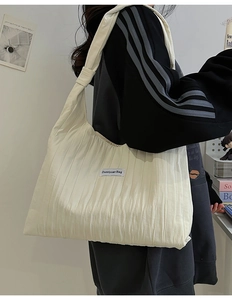 Detail of off-white pleated tote bag showing fabric texture and Duociyuan Bag logo tag